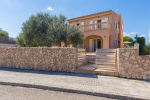a house with a stone wall and a fence at Dones Aigua in Colonia de Sant Pere