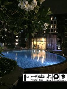 a large swimming pool in front of a building at night at nest condo in Ban Bang Toei (1)
