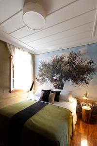 a bedroom with a large bed with a tree on the wall at Villa of the old olive oil factory in Ágios Konstantínos