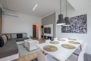 un soggiorno bianco con tavolo e sedie bianchi di blueWaveplace - Stylish 2 BR Home in Center of Sofia a Sofia