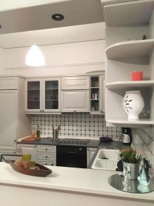 una cocina con armarios blancos y electrodomésticos negros en Cozy City Apt, en Heraclión