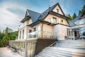 a large white house with glass balconies and stairs at NovaWisła Resort & SPA in Wisła