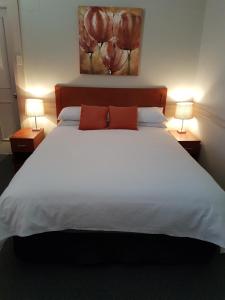 米塔贡Highlands Hotel的卧室里有一张白色的大床，床边还有两盏灯