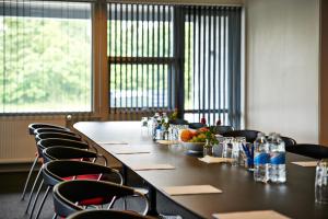 a long table with chairs in a room with windows at Motel Skive in Skive