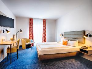 a hotel room with a bed and a desk at ACHAT Hotel Zwickau in Zwickau