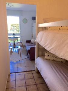 アンデルノ・レ・バンにあるAppart Les Goélands piscine et jardinのベッドルーム1室(ベッド1台付)、リビングルームが備わります。
