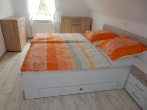 ein Schlafzimmer mit einem Bett mit einer orangen und weißen Bettdecke in der Unterkunft Ferienwohnung Gänseblümchen in Wartenburg
