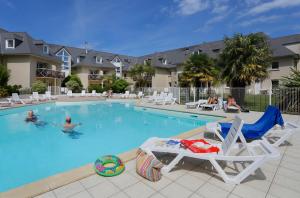 a swimming pool with chairs and people in a resort at Résidence Néméa Kermael in Saint-Briac-sur-Mer