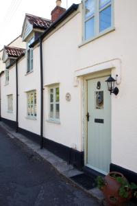 una casa blanca con una puerta blanca y una calle en Strawberry Cottage en Cheddar