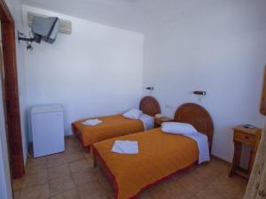 um quarto de hotel com duas camas e uma televisão em Hotel Lofos - The Hill em Ios Chora
