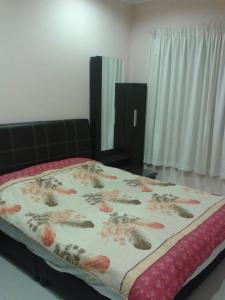 a bed in a bedroom with a floral bedspread at Rose Apartment Kea Farm in Cameron Highlands