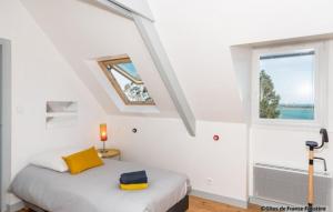 - une chambre avec un lit doté d'un oreiller jaune et d'une fenêtre dans l'établissement Le Gîte du Port, à Roscoff