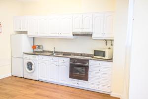 a white kitchen with white cabinets and a microwave at Arcadas Cozy Apartments - AV in Funchal