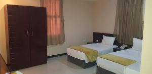 a hotel room with two beds and a cabinet at Sanabel Al Mish'an Furnished Units in Al Jithāmīyah