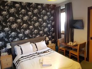 a bedroom with a bed with a black and white floral wallpaper at Alba Guest House in Aberdeen