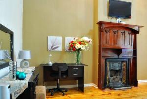 a room with a desk and a fireplace with a television at Tranquil Guest House in Dundee