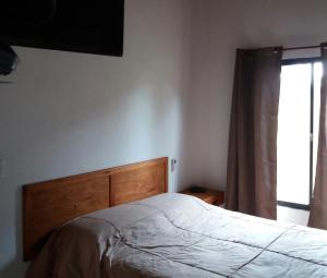 um quarto com uma cama com uma cabeceira em madeira e uma janela em La Araucana em Tacuarembó
