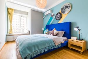 ein blaues Schlafzimmer mit einem Bett und einer blauen Wand in der Unterkunft Qingdao Shibei·Qingdao Wanda Plaza· Locals Apartment 00166560 in Qingdao