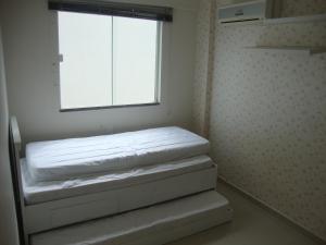Habitación pequeña con ventana y colchón en apartamento aluguel temporada bombinhas, en Bombinhas