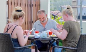two women and an older man sitting at a table eating food at Blue Water Boutique Hotel in Negombo