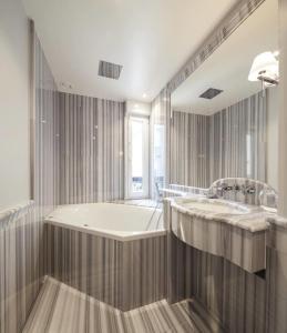 a large bathroom with a tub and a large mirror at Hôtel George Washington in Paris