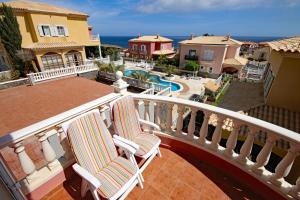 balcone con 2 sedie e piscina di LAS DUNAS 2 by RENTMEDANO Pretty 2 bedroom villa, ocean views, pool and WiFi a El Médano