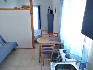 eine Küche mit einem Tisch, Stühlen und einem Waschbecken in der Unterkunft Apartment More OTOK Žirje in Žirje