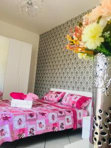 a bedroom with a pink bed and a vase with flowers at Lisa’s House in Naples