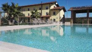 a swimming pool with chairs and a building in the background at Agriturismo San Gallo in Strassoldo