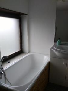 een badkamer met een wit bad en een raam bij Le p'tit gîte d'Enhet in Ciney
