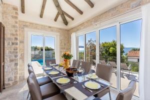 a dining room with a table and chairs and windows at Villa Lurda Linardici Krk in Linardići