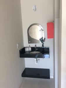 een badkamer met een wastafel en een spiegel bij Suíte Triplex in Capitólio