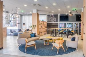 a waiting area with chairs and tables and a library at Madrid Airport Suites, Affiliated by Meliá in Madrid