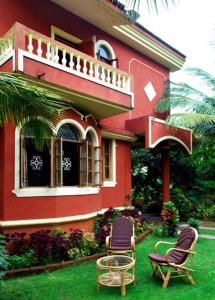 uma casa vermelha com duas cadeiras à frente em Victoria Villa em Sinquerim