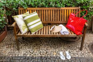 a wooden bench with pillows and a red bag at Hotel Vermont Ipanema in Rio de Janeiro