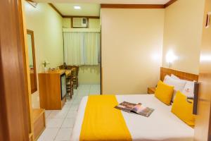 a hotel room with a bed with a yellow blanket at Hotel Vermont Ipanema in Rio de Janeiro