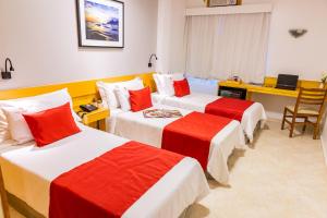 a room with three beds with red and white sheets at Hotel Vermont Ipanema in Rio de Janeiro