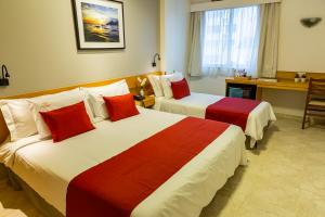 a hotel room with two beds with red and white pillows at Hotel Vermont Ipanema in Rio de Janeiro