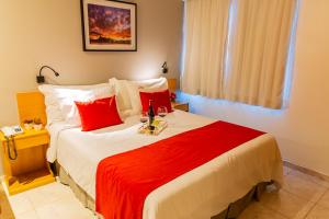 a bedroom with a large bed with red pillows at Hotel Vermont Ipanema in Rio de Janeiro