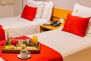 a hotel room with two beds with a tray of food at Hotel Vermont Ipanema in Rio de Janeiro