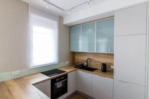 uma cozinha com armários brancos e um lavatório em Apartamenty City Tower od WroclawApartament-pl em Breslávia