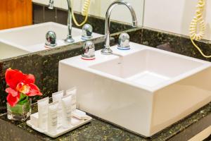 a bathroom sink with a red flower on a counter at Hotel Vermont Ipanema in Rio de Janeiro