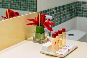 a bathroom counter with a red flower in a vase at Hotel Vermont Ipanema in Rio de Janeiro