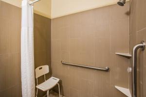a bathroom with a shower with a toilet and a chair at Super 8 by Wyndham Altoona in Altoona +31 photos