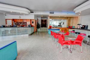 un restaurante con mesas y sillas rojas y una barra en Geneva Hotel, en Miami Beach