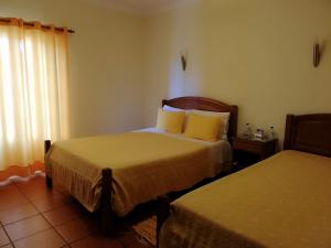 a hotel room with two beds and a window at Residencial Idalio in Odemira