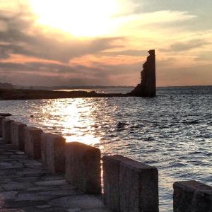 a sunset over a body of water with a lighthouse at Parador de Cambados in Cambados