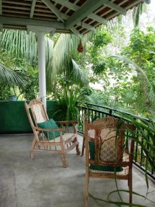 two chairs on a porch with trees in the background at Unawatuna Backpacker Lodge in Unawatuna
