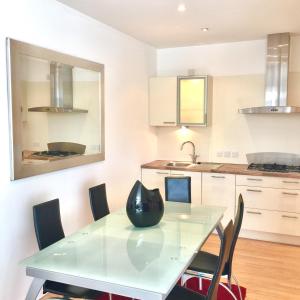 a kitchen with a glass table and chairs at River Clyde West End Apartment - 2 Bedrooms in Glasgow