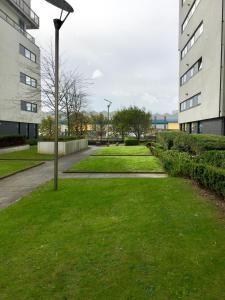 a park with green grass and buildings and a pole at River Clyde West End Apartment - 2 Bedrooms in Glasgow